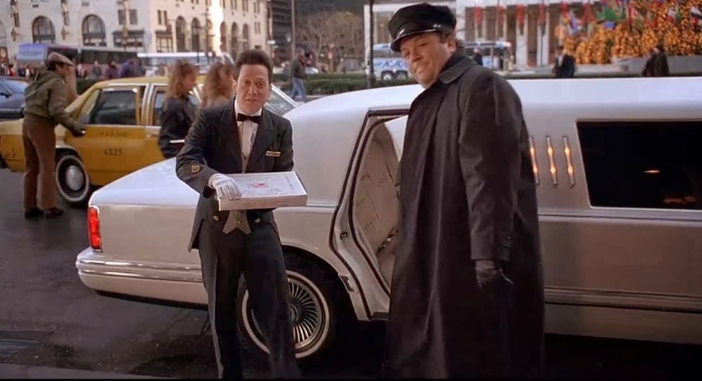 a man in a suit holding a box next to a man in a car