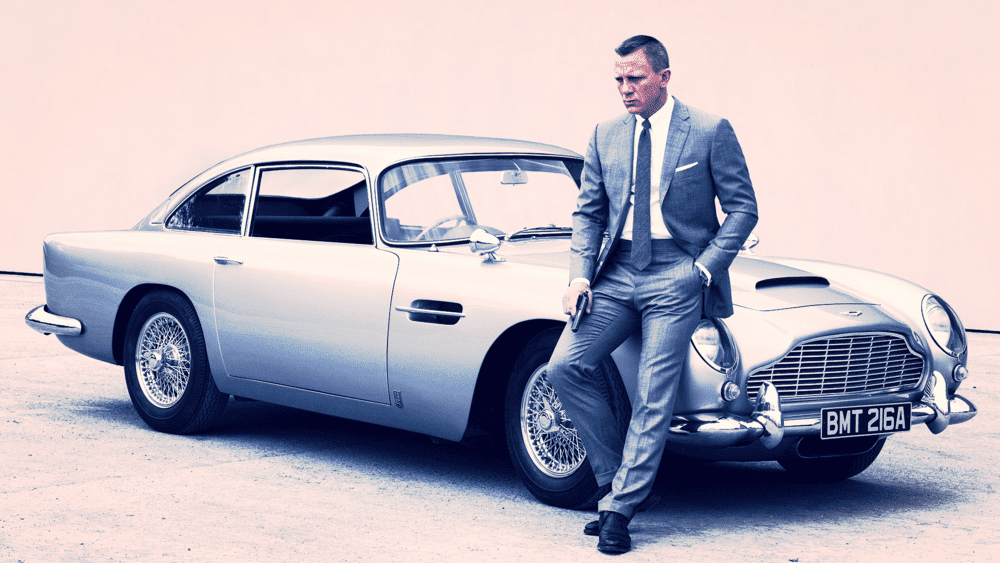 a man in a suit leaning on a car