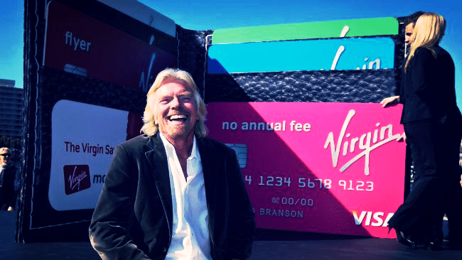 a man smiling in front of a large sign