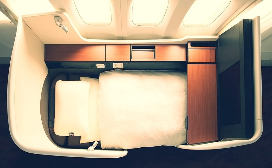 an airplane bed with a white pillow and a white blanket