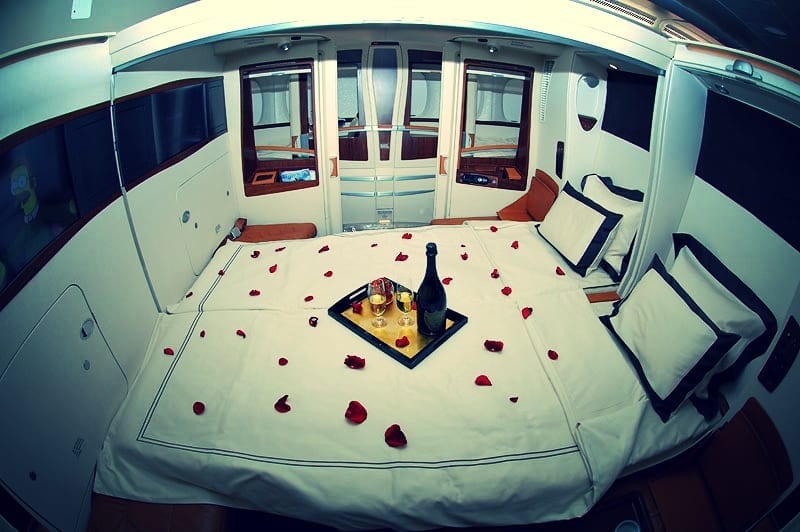 a bed with a tray of wine and rose petals