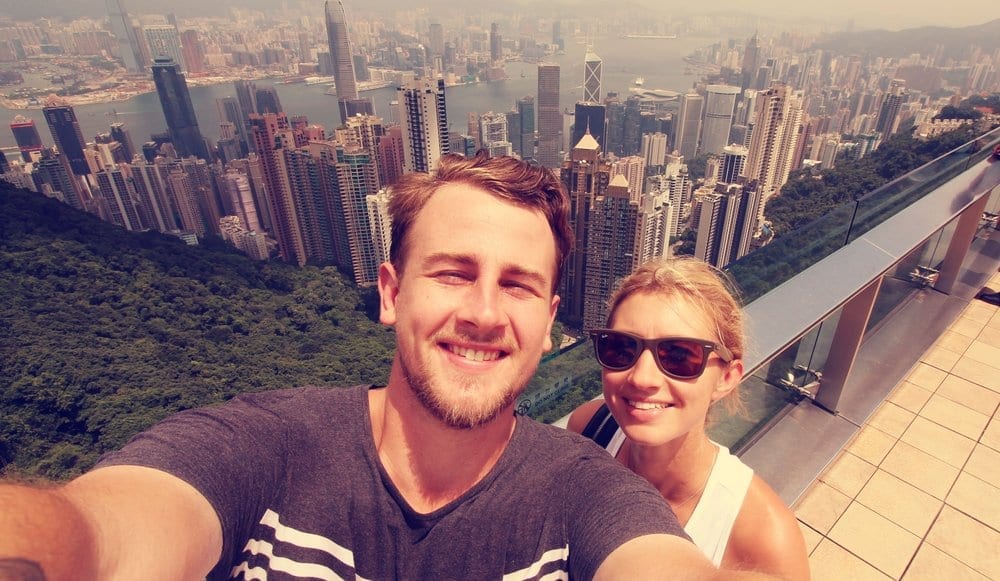a man and woman taking a selfie with a city in the background