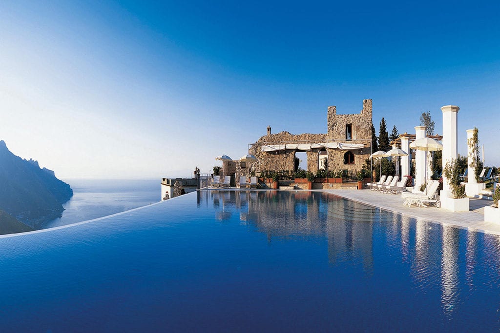 a pool with a stone building and a stone castle on the edge