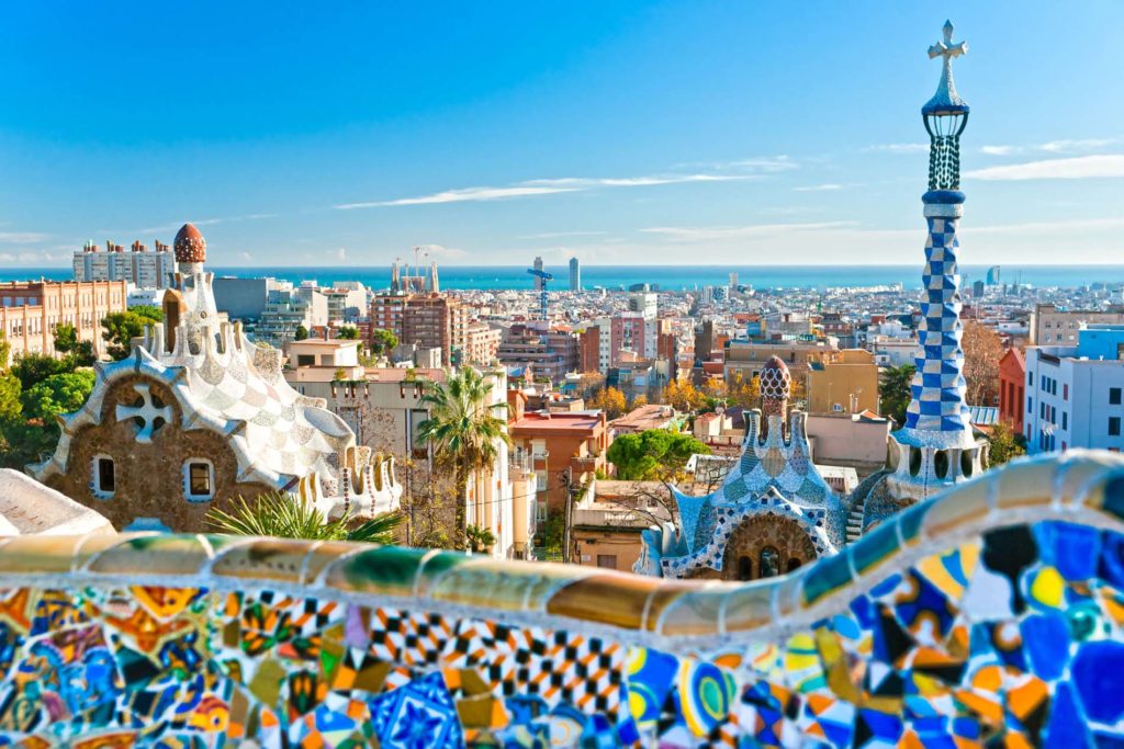 a colorful tiled rooftops with Park Güell in the background
