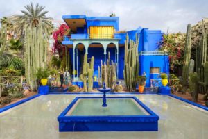 a blue house with a fountain and cacti
