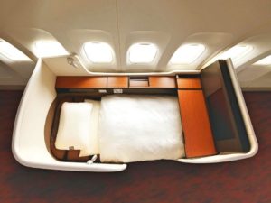 an airplane bed with a white pillow and a wood cabinet