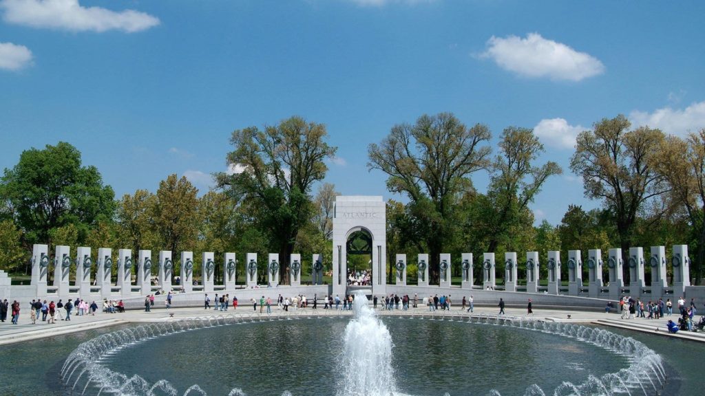 a group of people around a fountain with National World War II Memorial in the background
