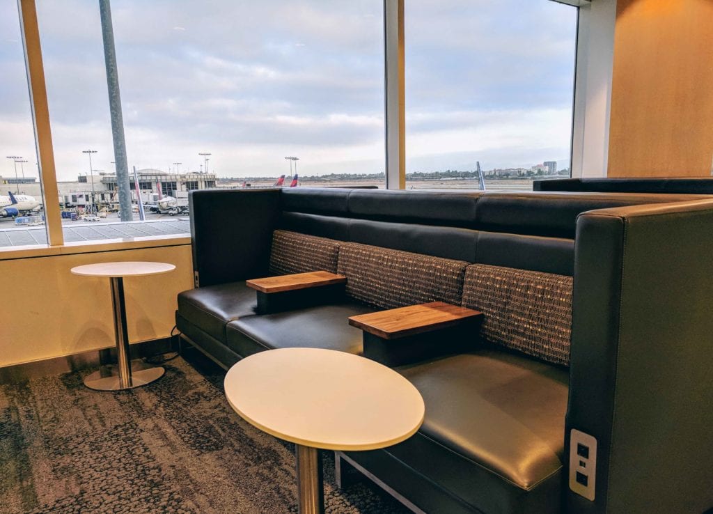 a booth with tables and chairs in a room with a view of an airport