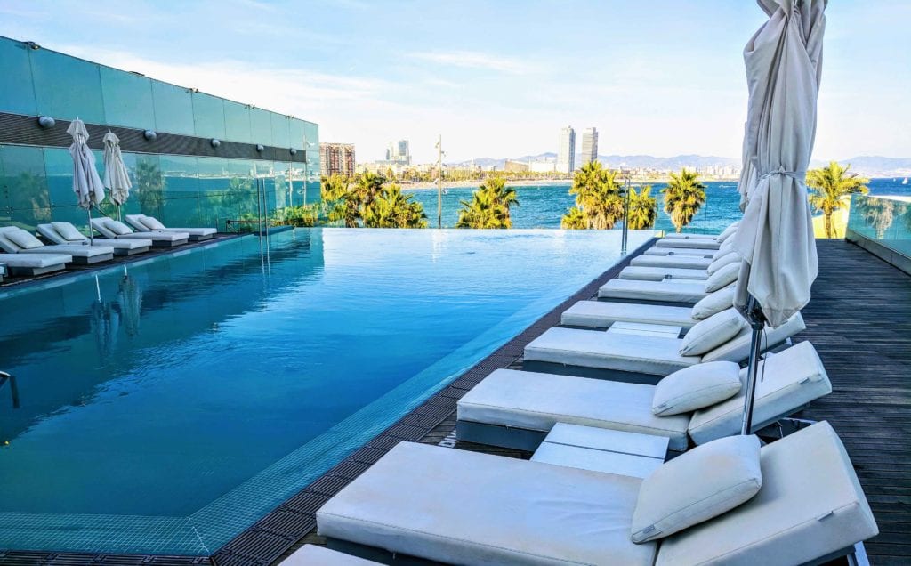 a pool with lounge chairs and a body of water