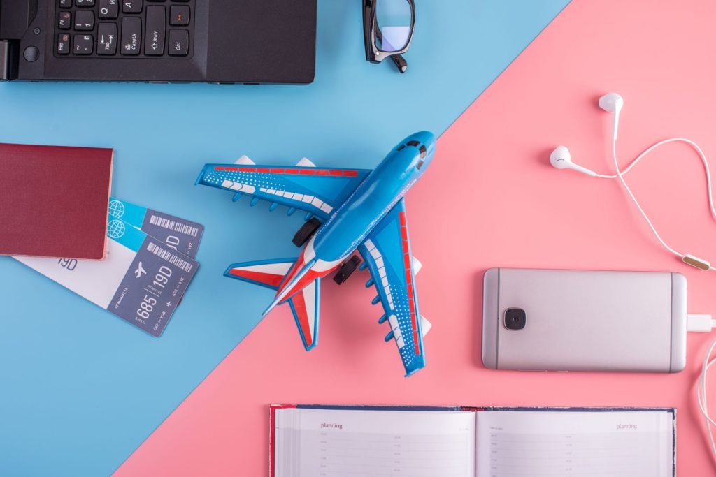 Plane, air tickets, passport, notebook and phone with headphones on pastel background. The view from the top. The concept of planning and preparing for the travel