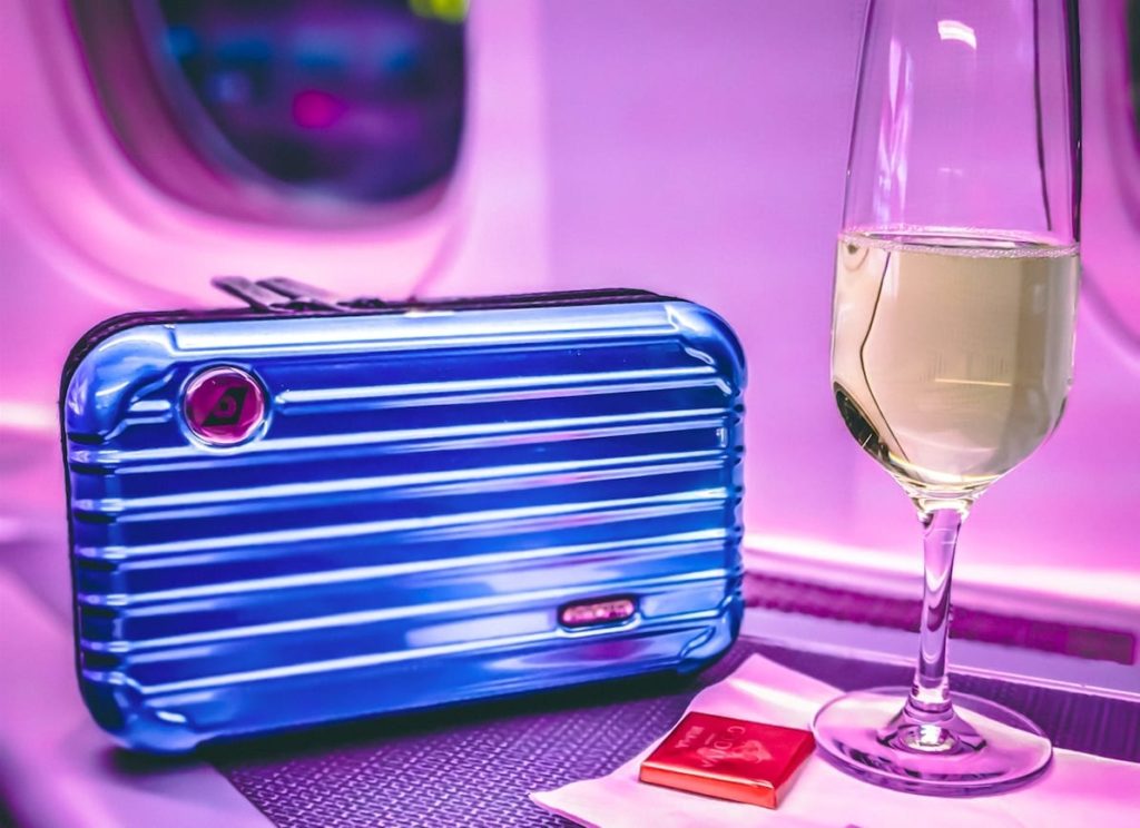 a glass of wine next to a blue suitcase
