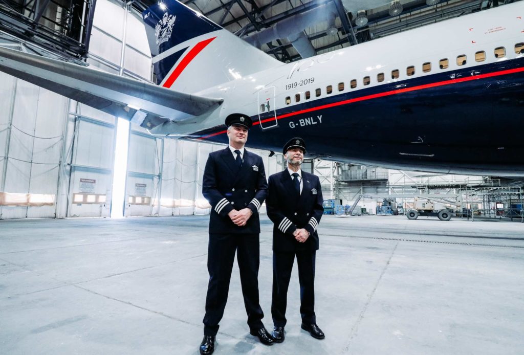 two men in uniform standing in front of an airplane