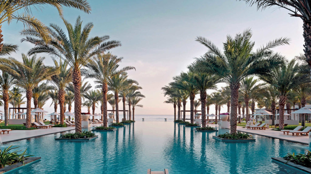 a pool with palm trees and chairs and umbrellas