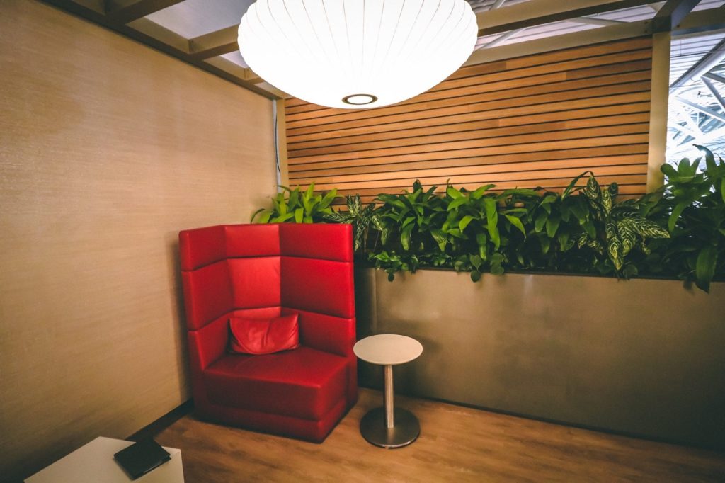 a red chair and a table in a room with plants