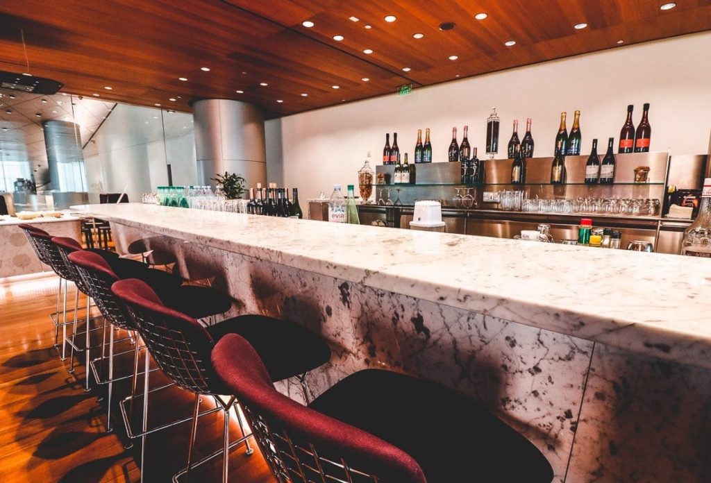 a bar with chairs and bottles of alcohol
