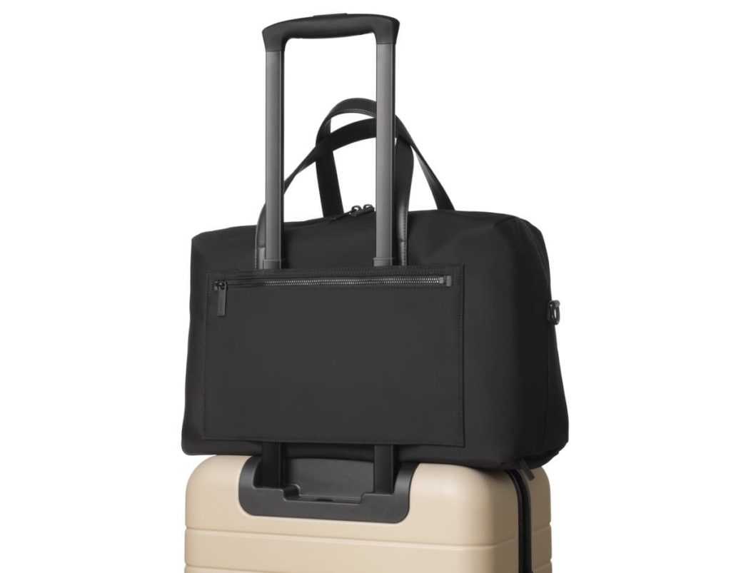 a black bag on top of a tan suitcase