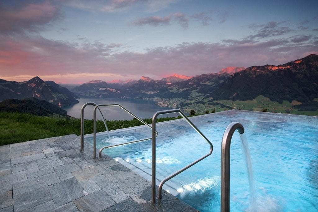 a pool with a body of water and mountains in the background
