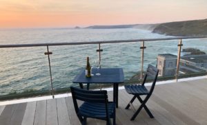a table and chairs on a deck overlooking the ocean