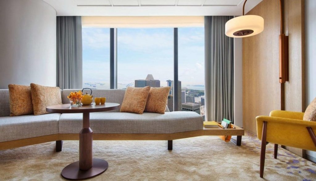 a couch with a table and a round table in a room with a view of a city