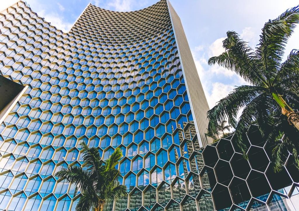 a tall building with hexagons and palm trees