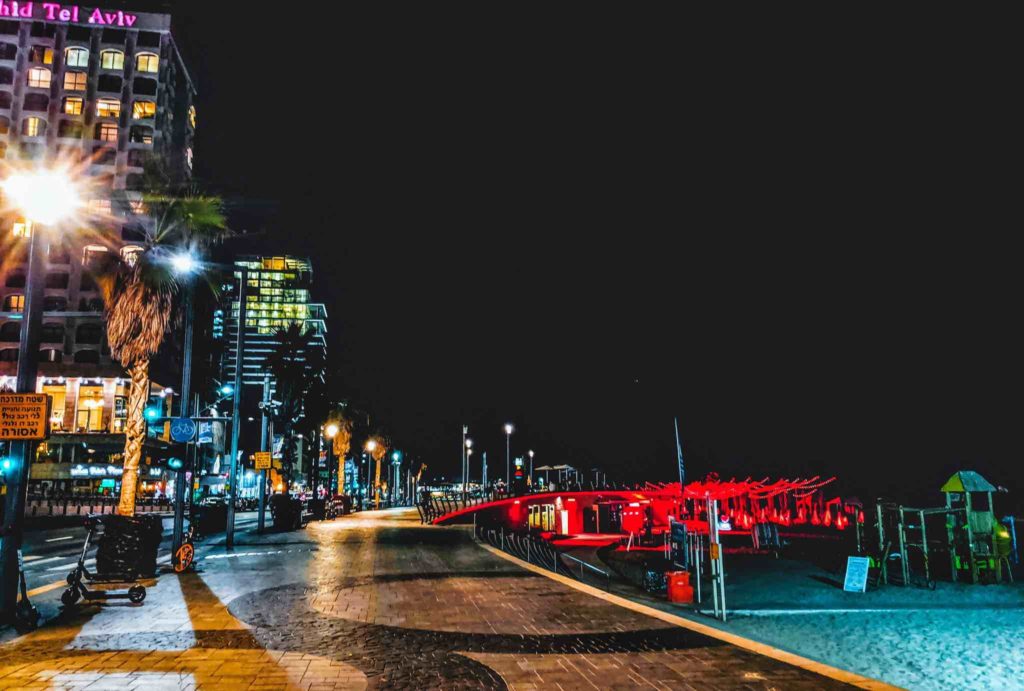 a street with a red bridge and buildings at night