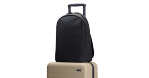 a black backpack on top of a tan suitcase
