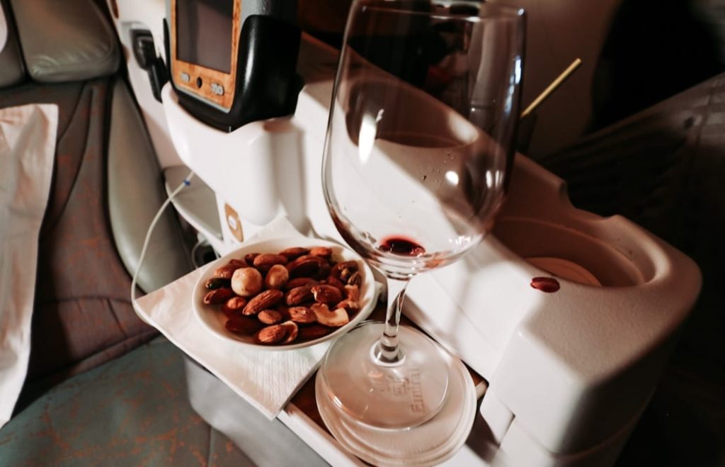 a plate of nuts and a glass of wine on a tray