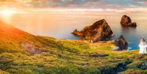 Scenic panorama of Cape Brett lighthouse on the coast of New Zealand during sunset. Located in Bay of Islands, popular tourist destination for its natural beauty.
