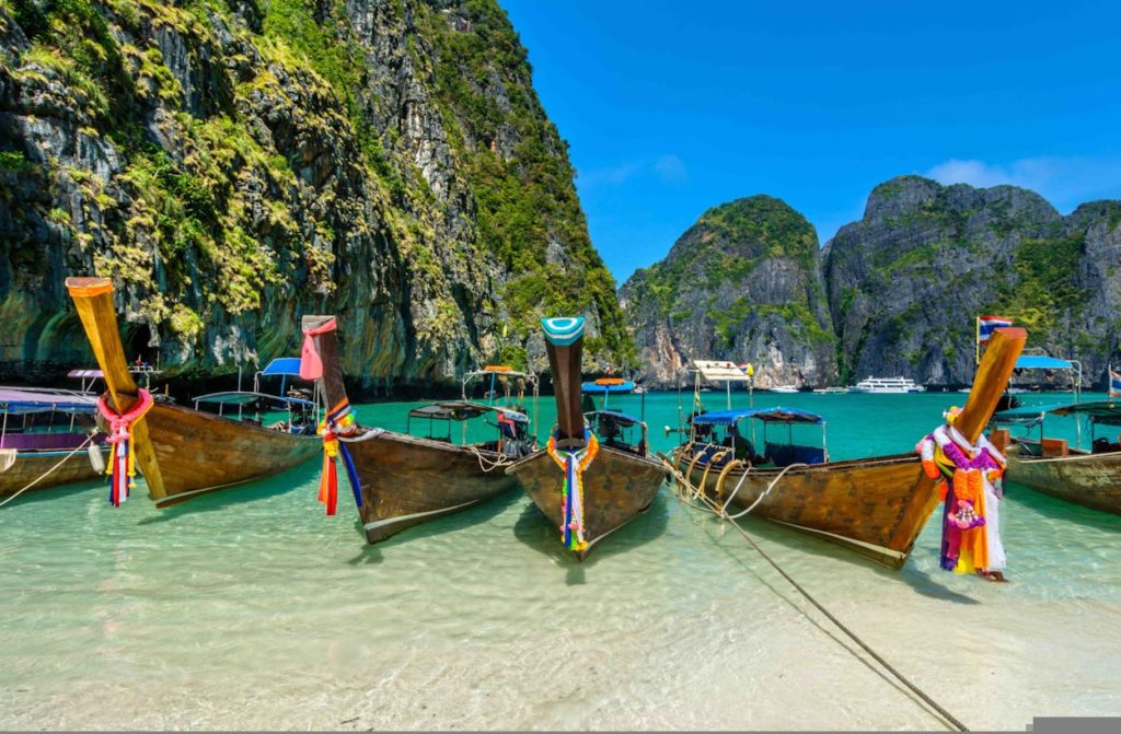 boats in a body of water with mountains in the background with Phi Phi Islands in the background