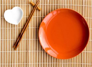 an orange plate and chopsticks on a bamboo mat