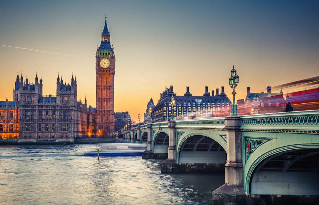 a bridge over a river with a clock tower in the background