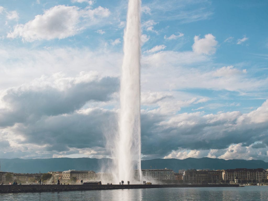a water spouting up from a fountain with Jet d'Eau in the background