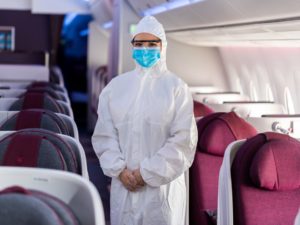 a person in a white suit and mask standing in an airplane