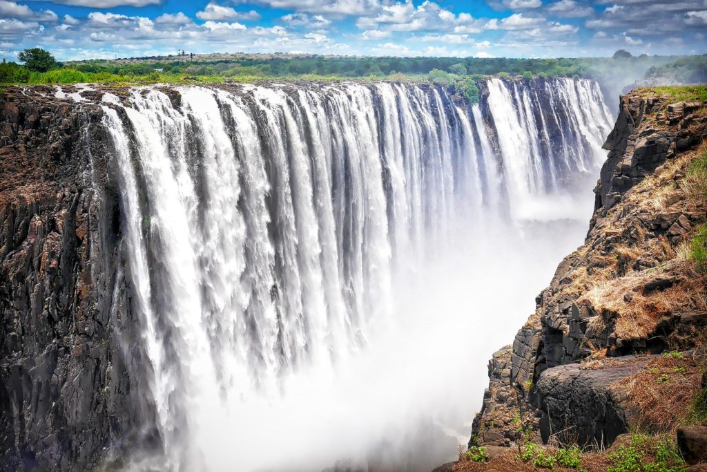 a large waterfall with a lot of water falling with Victoria Falls in the background