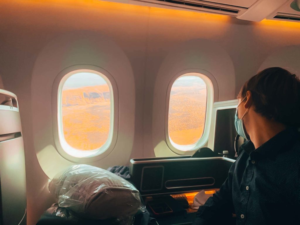 a person in a mask looking out of an airplane window