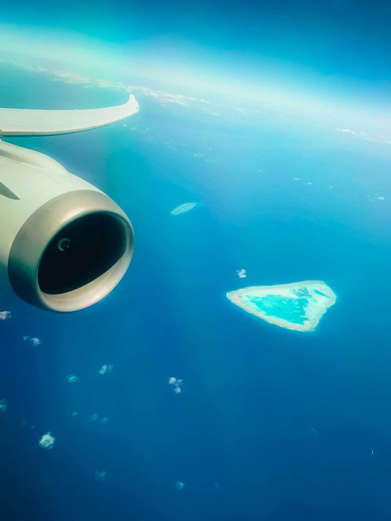 an airplane wing and a small island in the ocean
