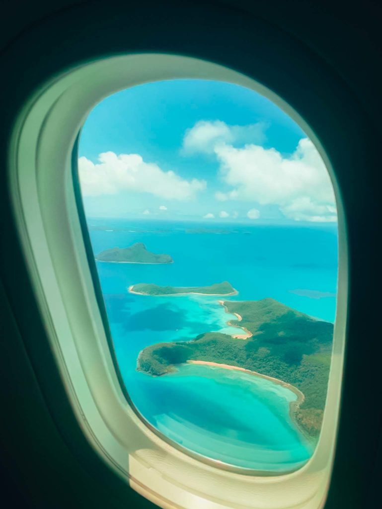 an airplane window with islands and blue water