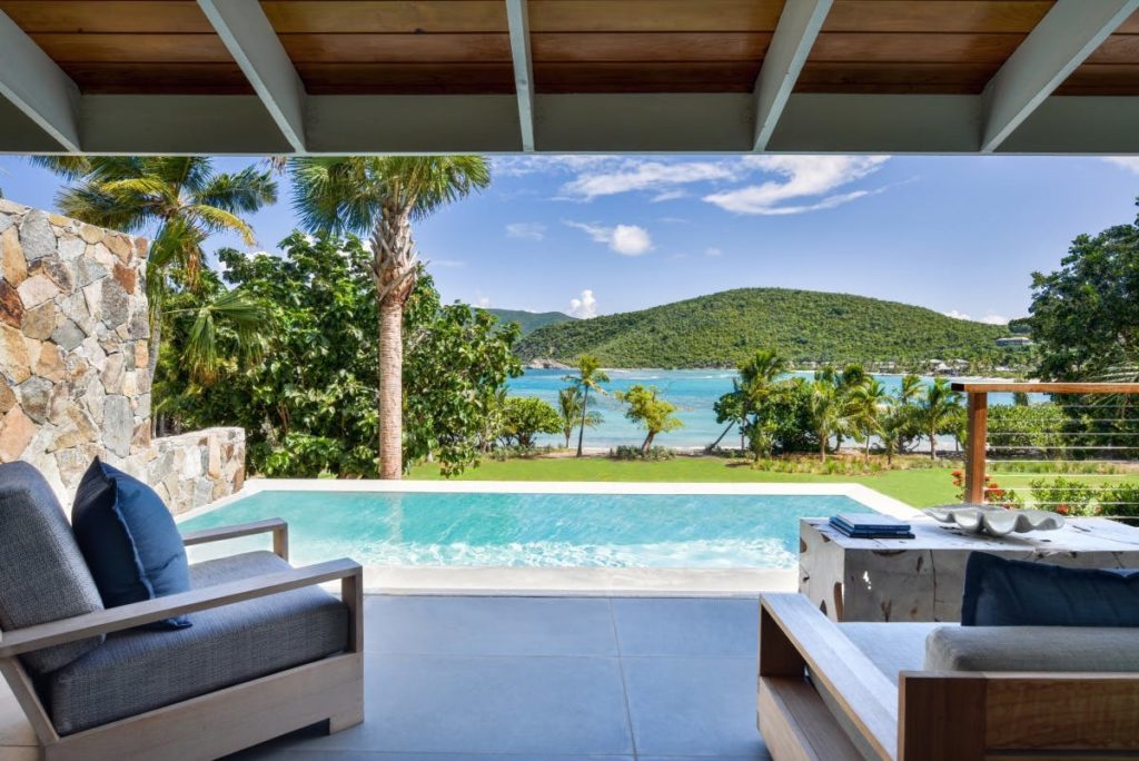 a pool with a view of the ocean and a hill in the background