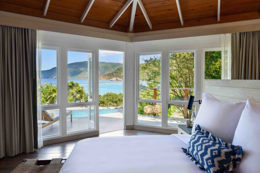 a room with a large bed and a pool and a view of the ocean