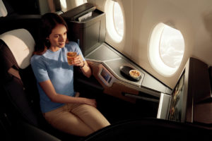 a woman sitting in an airplane drinking a drink