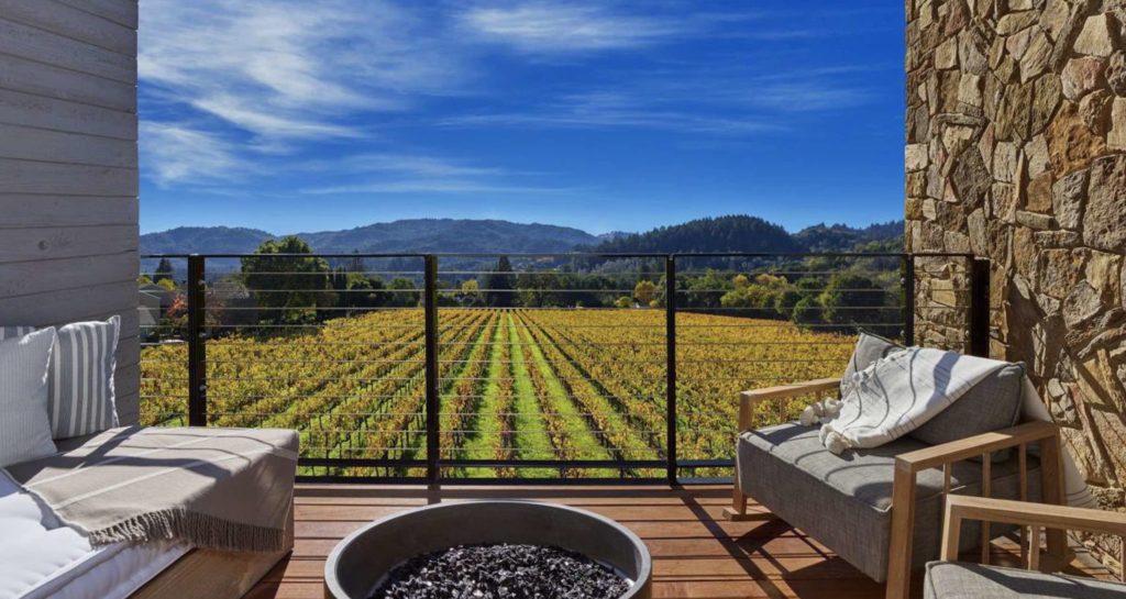 a patio with chairs and a fire pit overlooking a vineyard