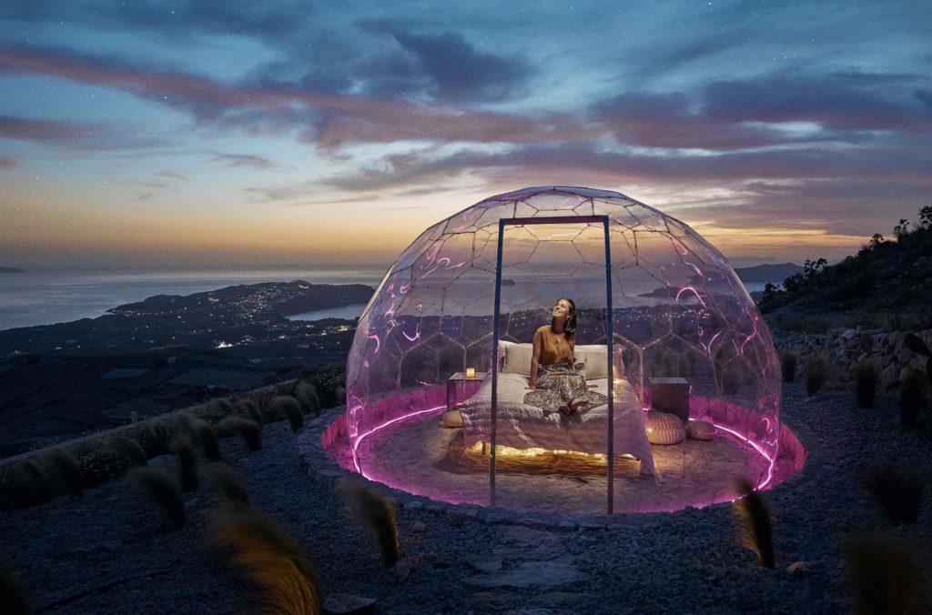 a woman sitting on a bed in a glass dome