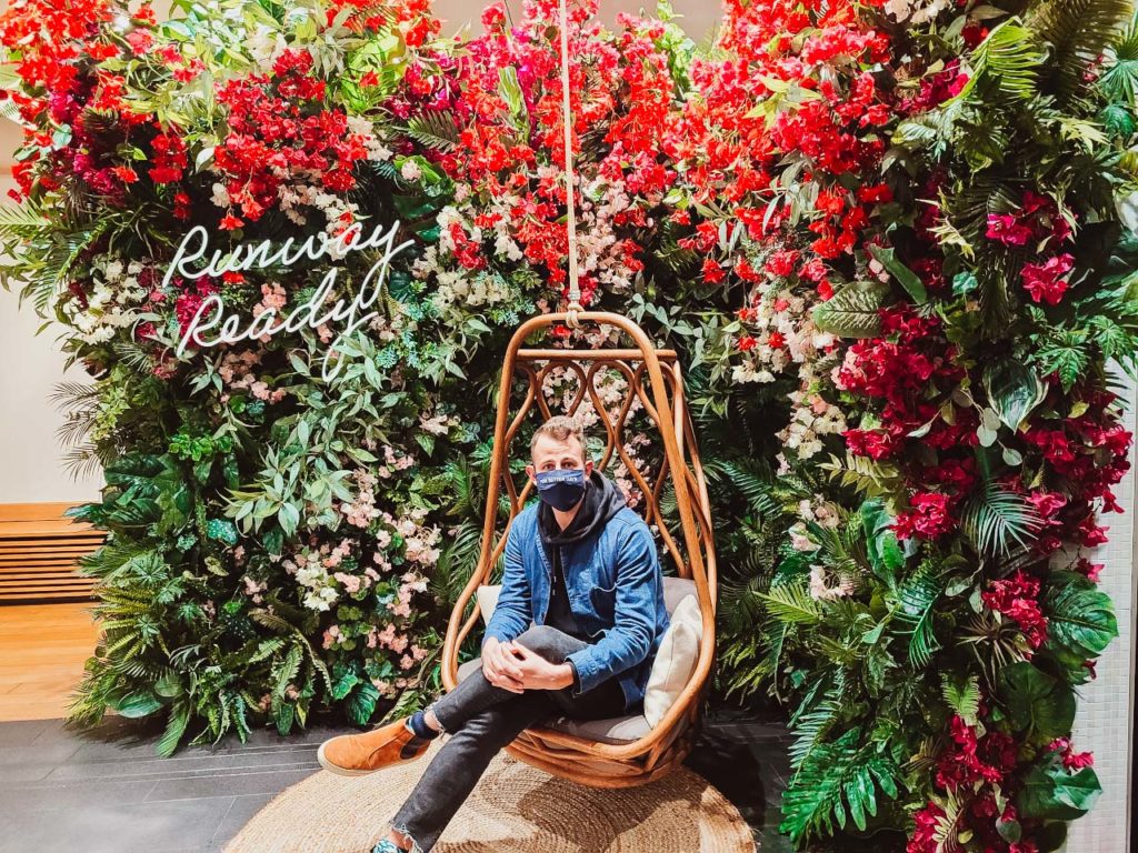 a man wearing a face mask sitting in a chair with flowers