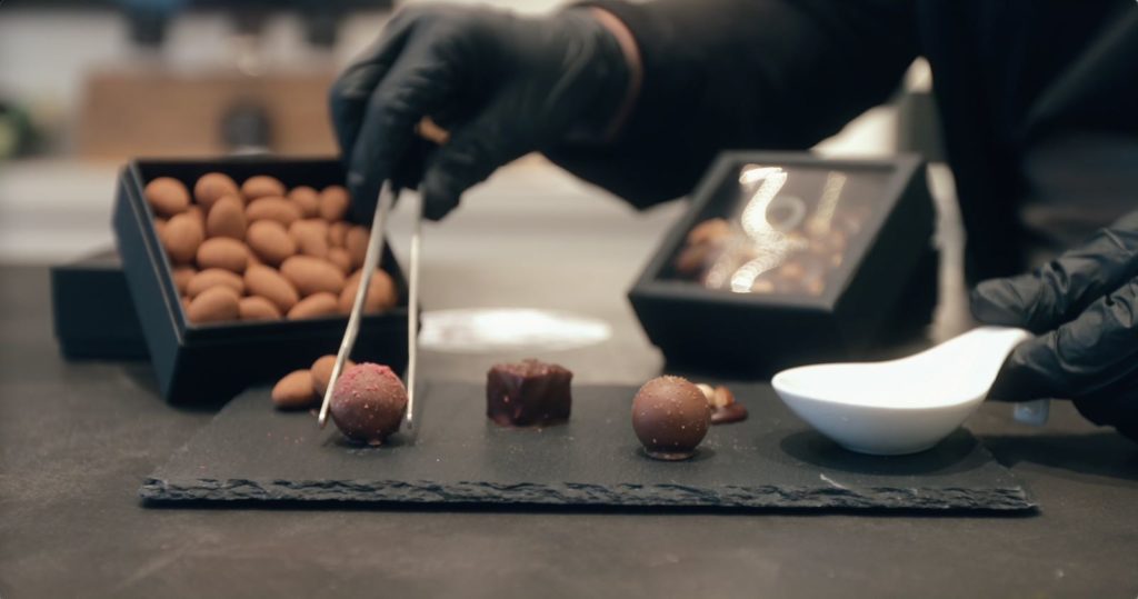 a person holding tweezers to a chocolate truffle