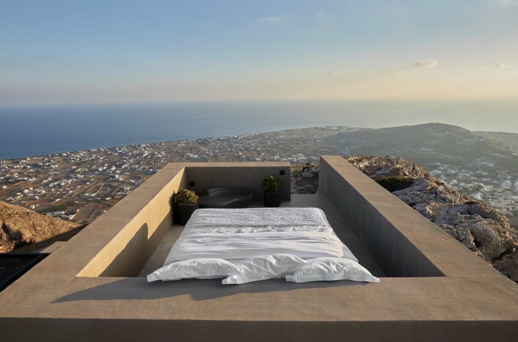 a bed on a ledge overlooking a city