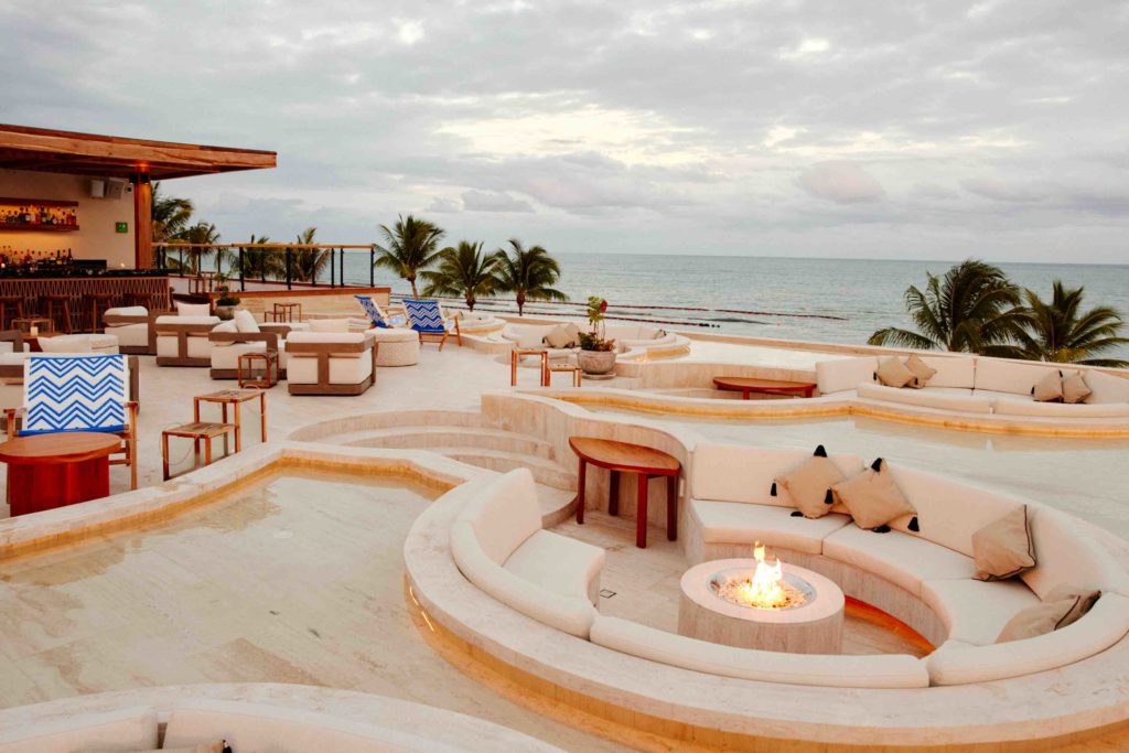 a pool with chairs and tables on a beach