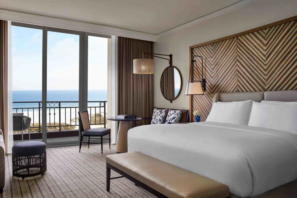 a room with a bed and a balcony overlooking the ocean