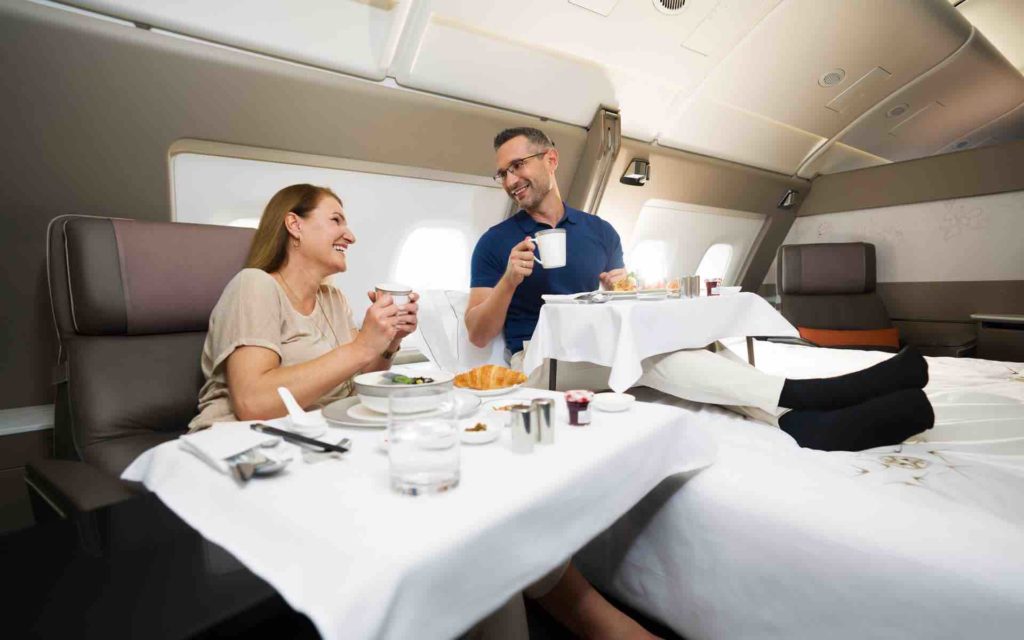 a man and woman sitting at a table in an airplane