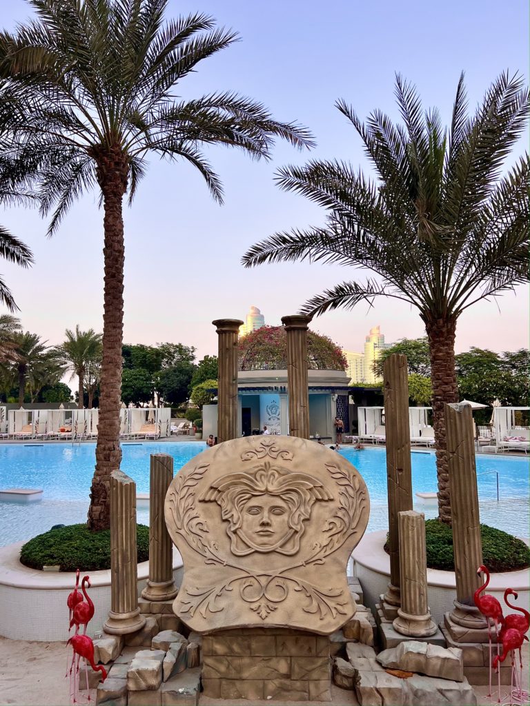 a pool with palm trees and a sculpture