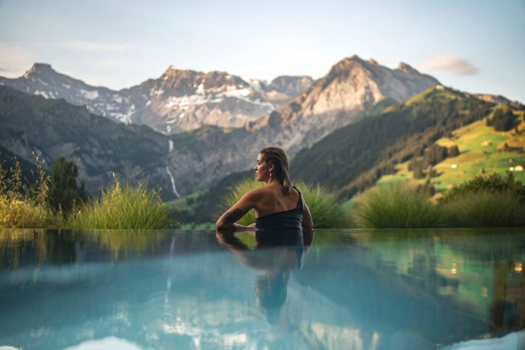 a woman sitting on a pool with mountains in the background